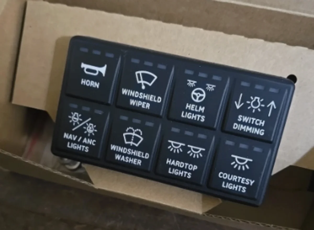An 8-way physical digital switch panel, unboxed, with labeled buttons for horn, wiper, helm lights, switch dimming, nav/anchor lights, washer, hardtop lights, and courtesy lights
