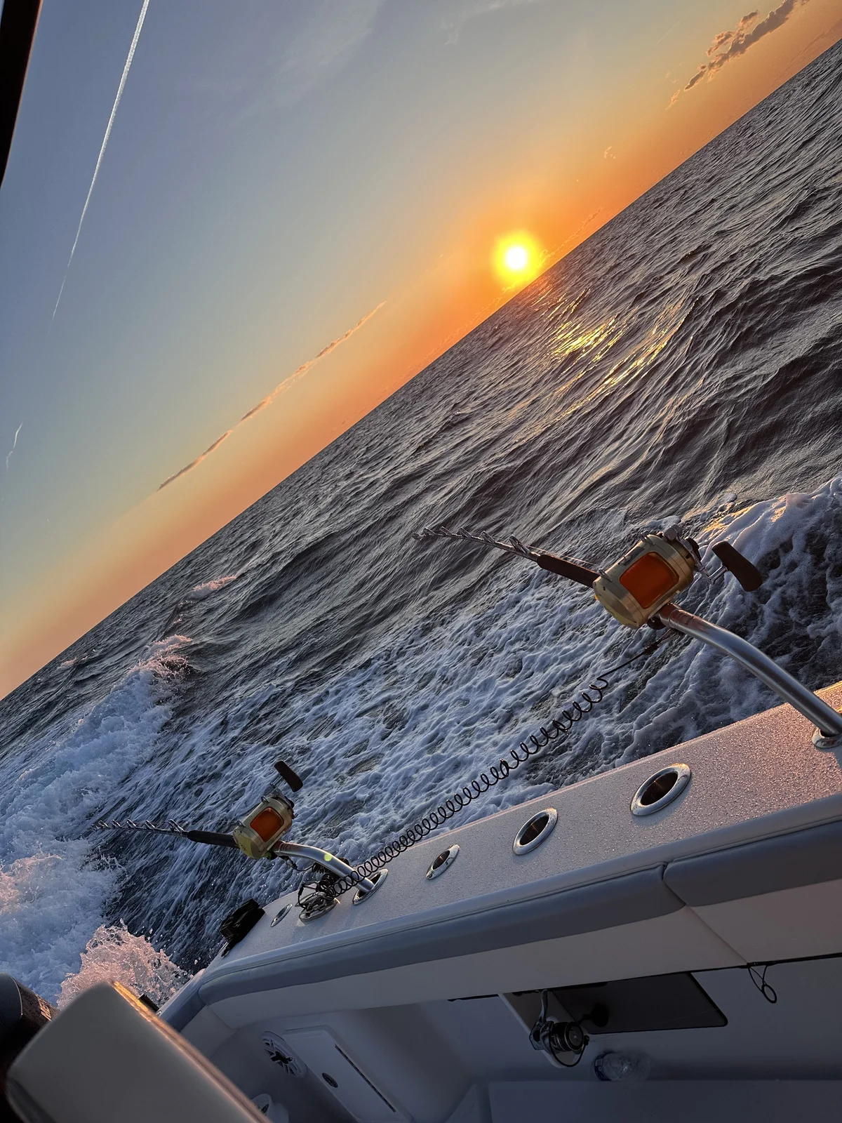 Two conventional reels loaded with wire and trolling weight, running high-speed at sunrise